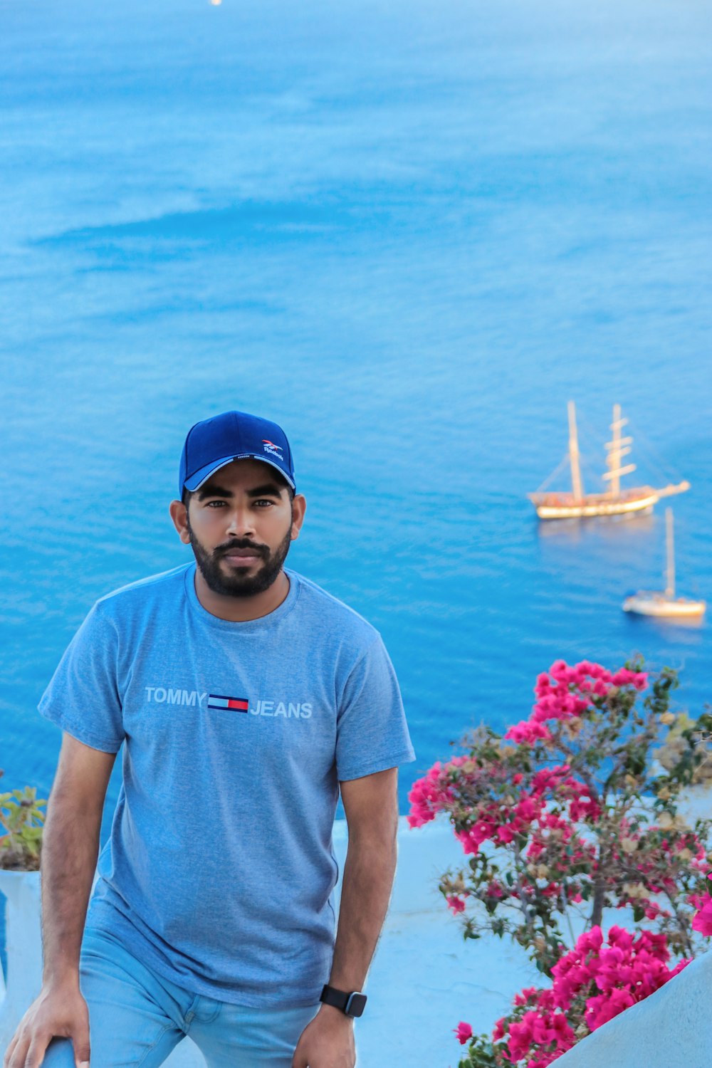 man in gray crew neck t-shirt and blue fitted cap standing near body of water