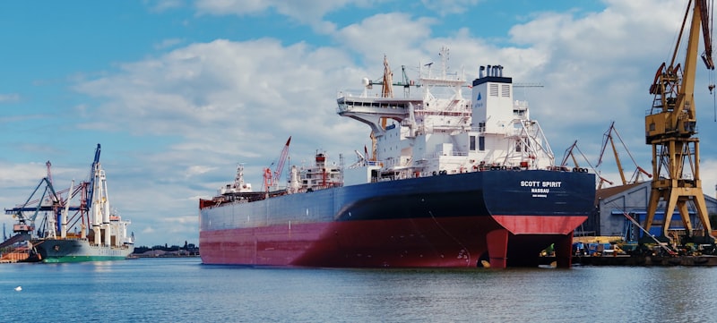 Red and white cargo ship at sea under cloudy skies