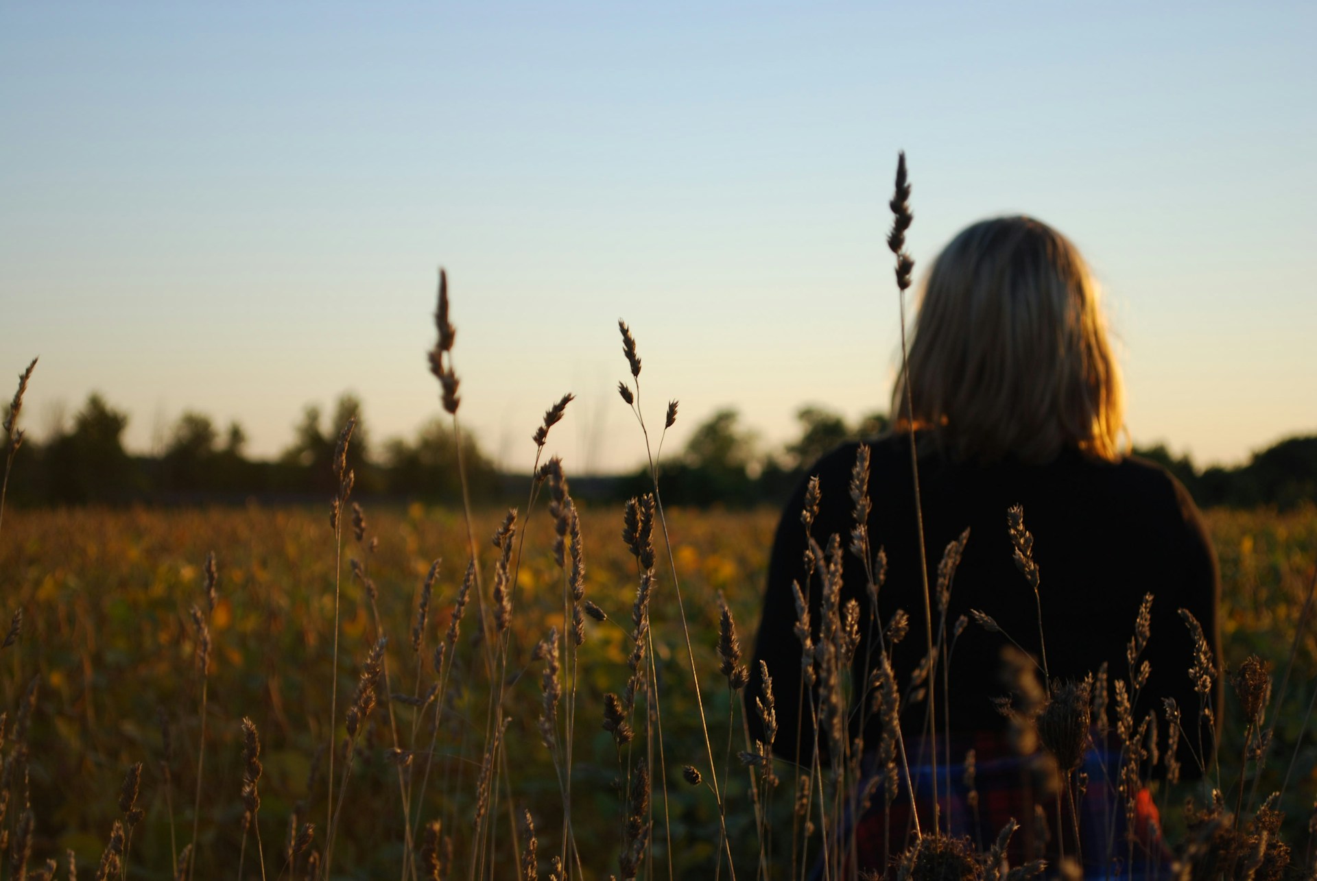 woman in black and white floral long sleeve shirt standing on green grass field during daytime