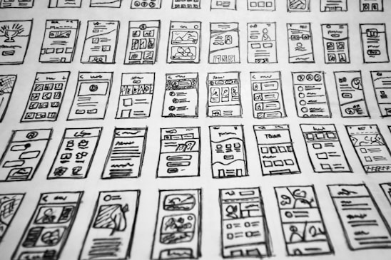 Multiple hand-drawn sketches of mobile user interface designs are spread out in a grid pattern. Each sketch contains various UI elements such as buttons, text boxes, images, and icons.