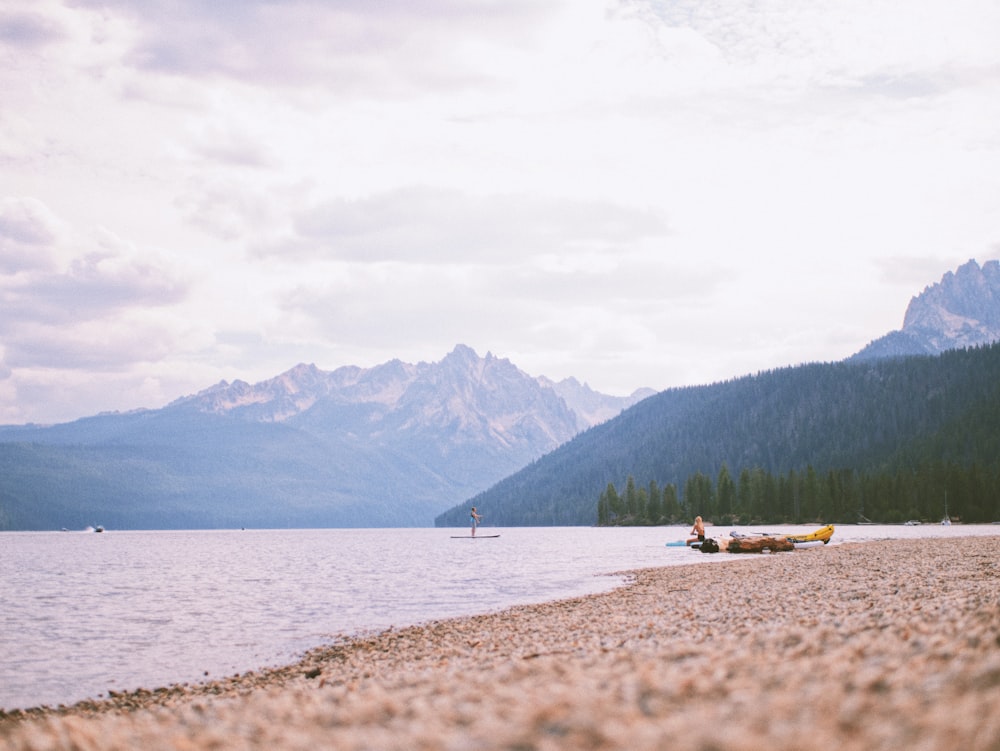 people on lake near mountains during daytime