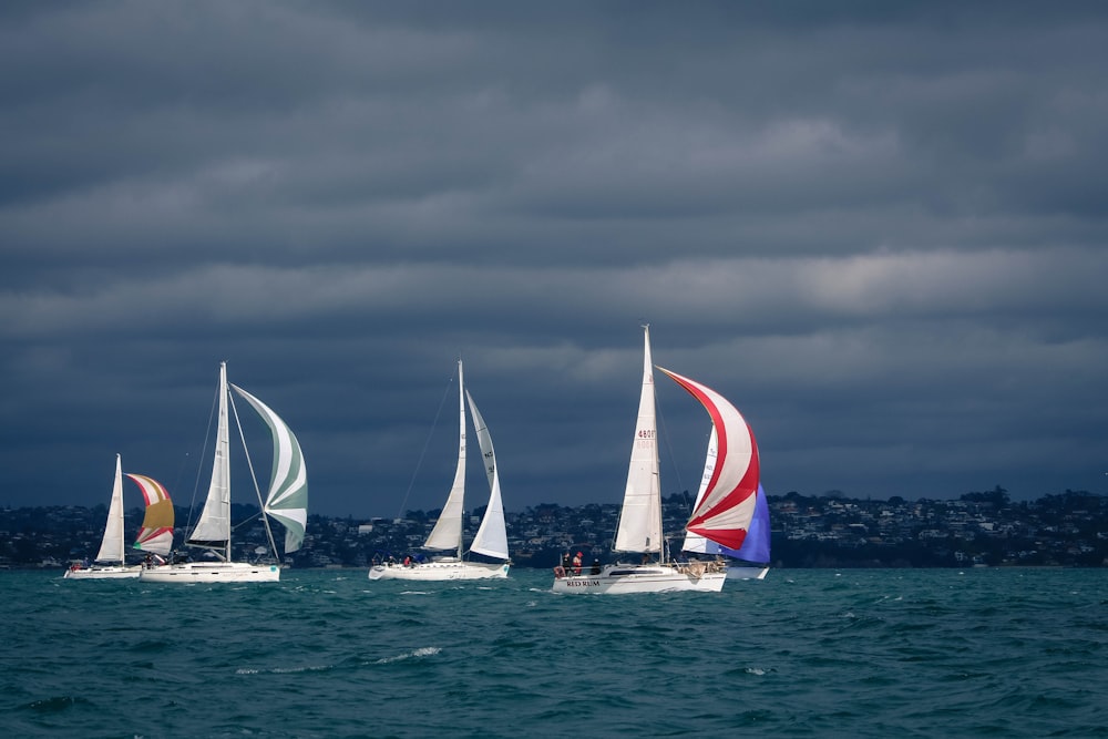 white sail boat on sea under gray clouds