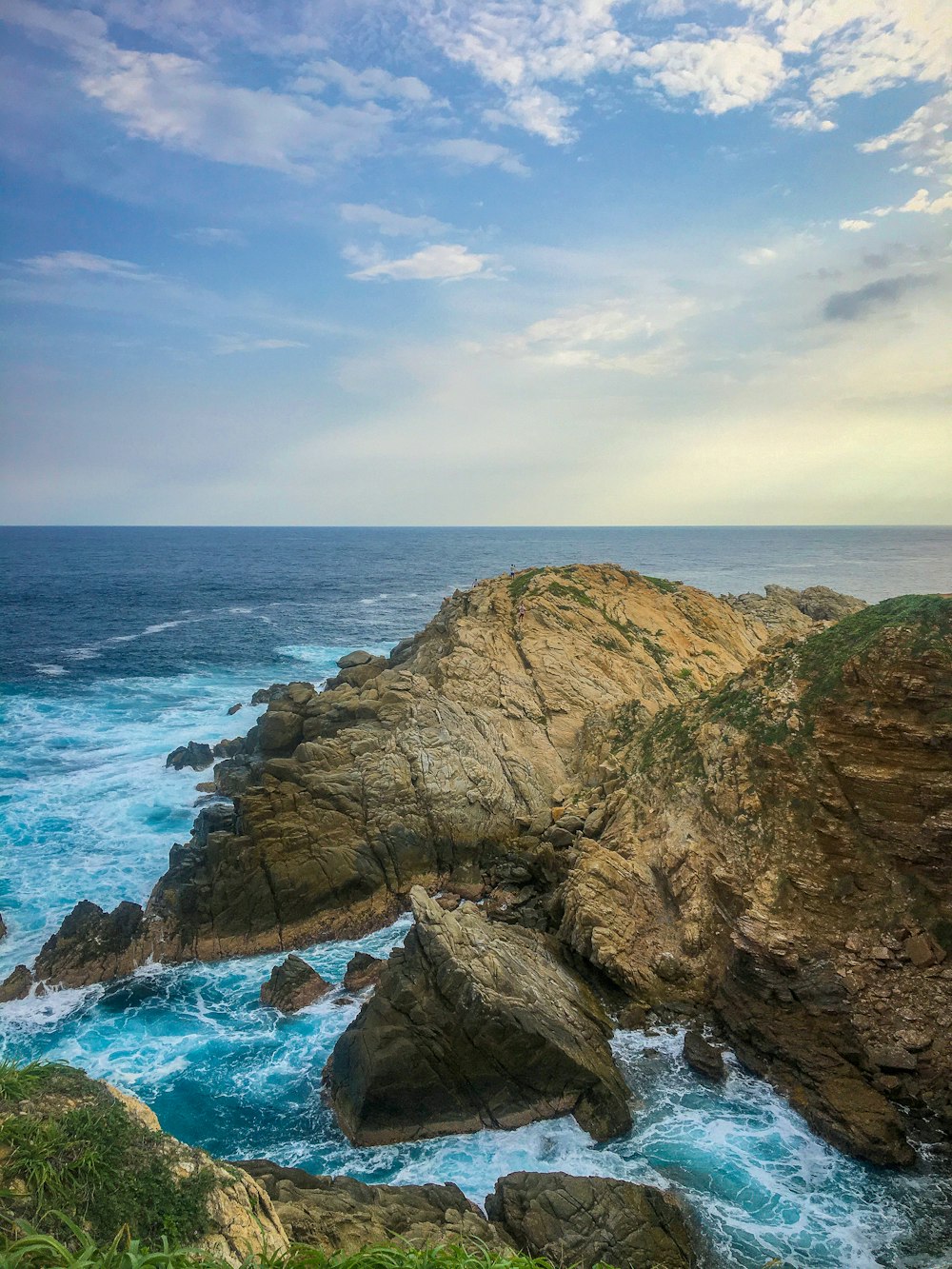 brown rocky mountain beside blue sea under blue sky during daytime