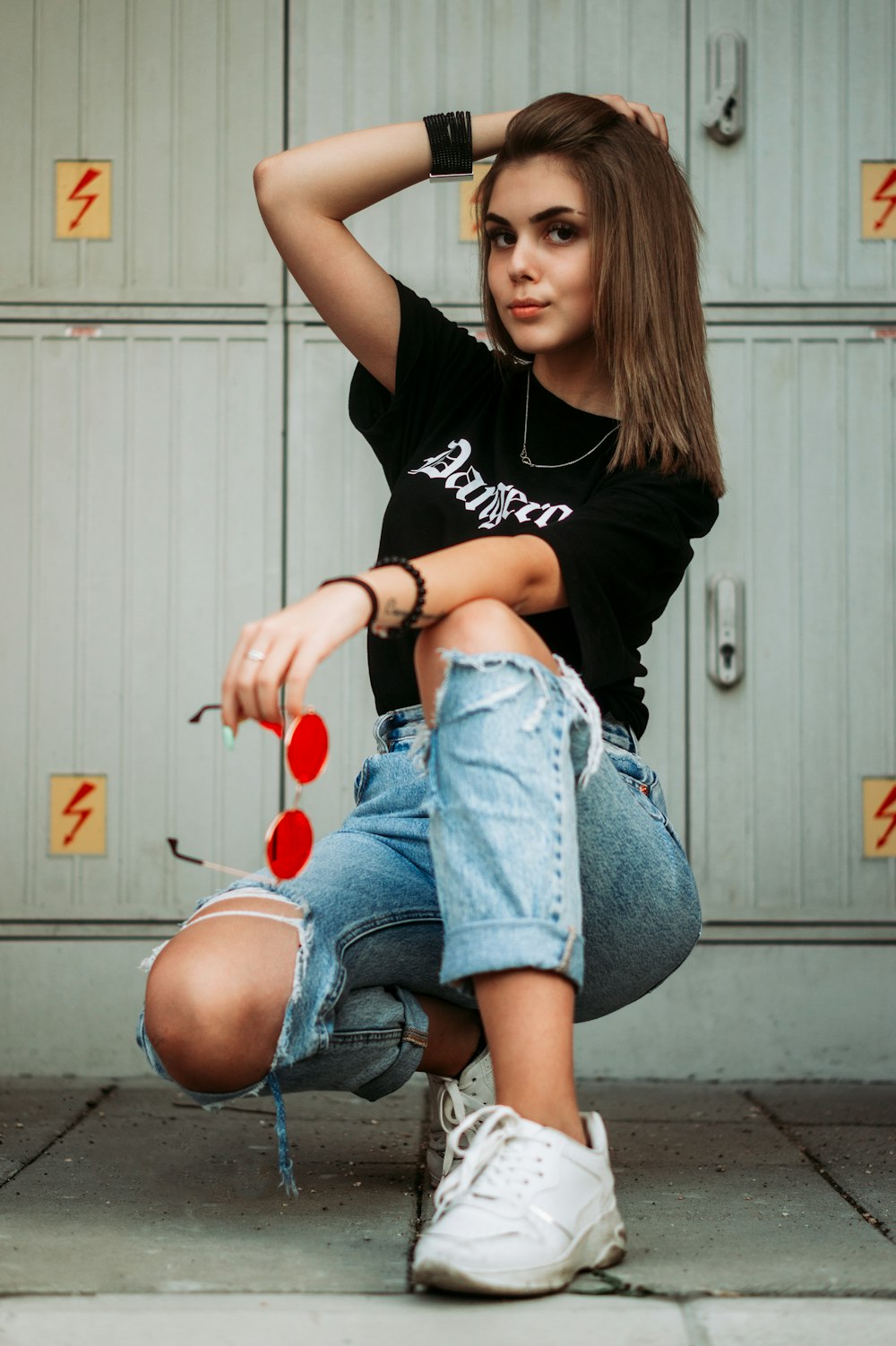 woman in black t-shirt and blue denim shorts sitting on gray concrete floor