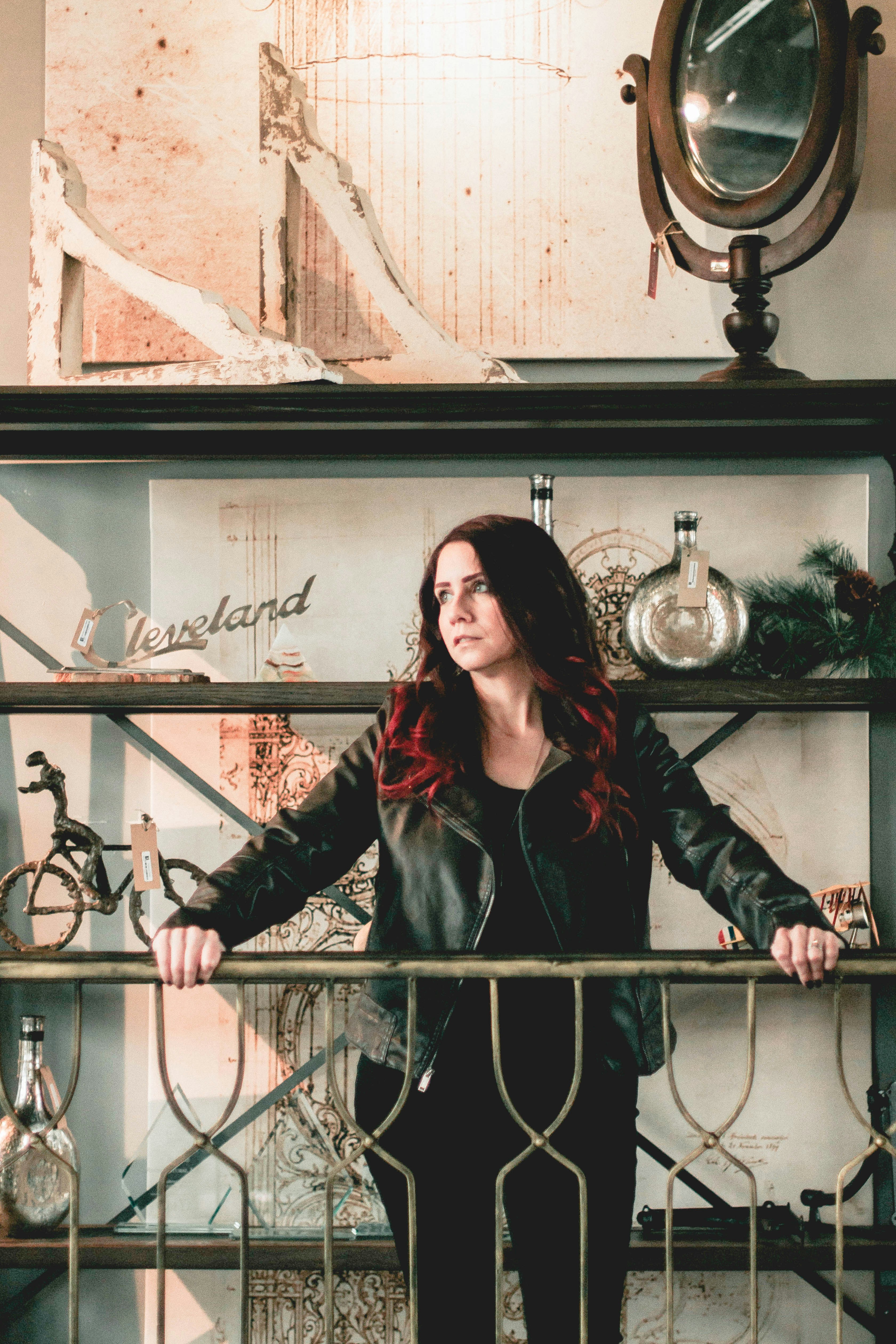 woman in black leather jacket standing beside black metal fence