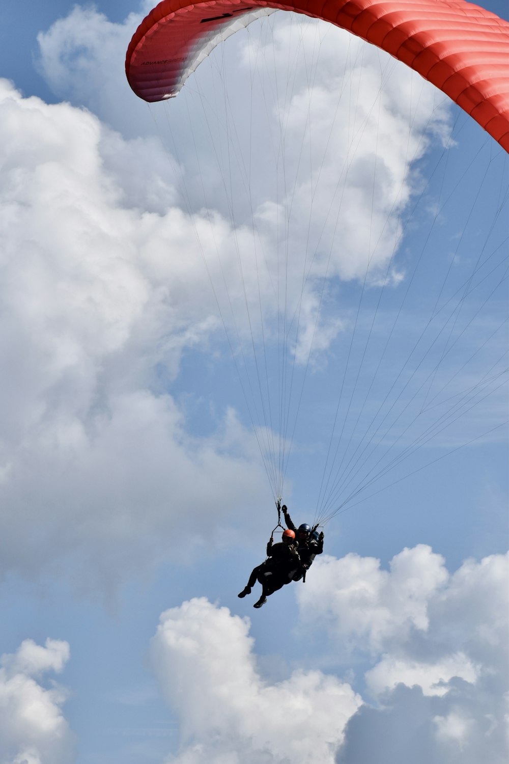 Persona con chaqueta negra y pantalones negros haciendo paracaidismo durante el día