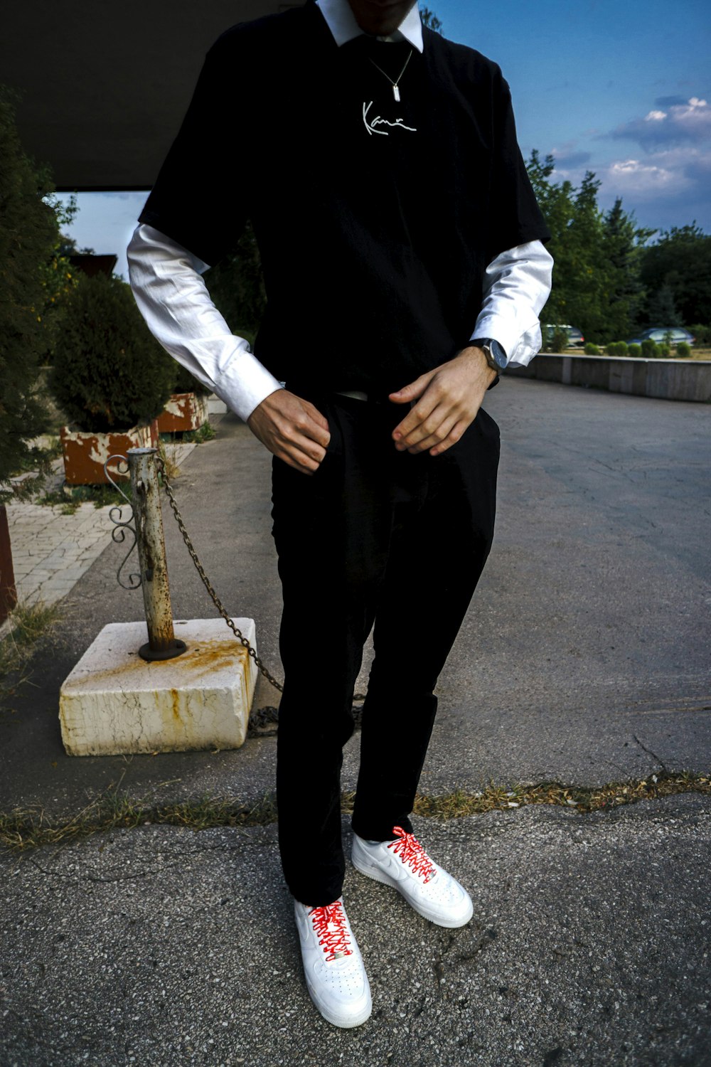 person in black pants and white long sleeve shirt standing on gray asphalt road during daytime