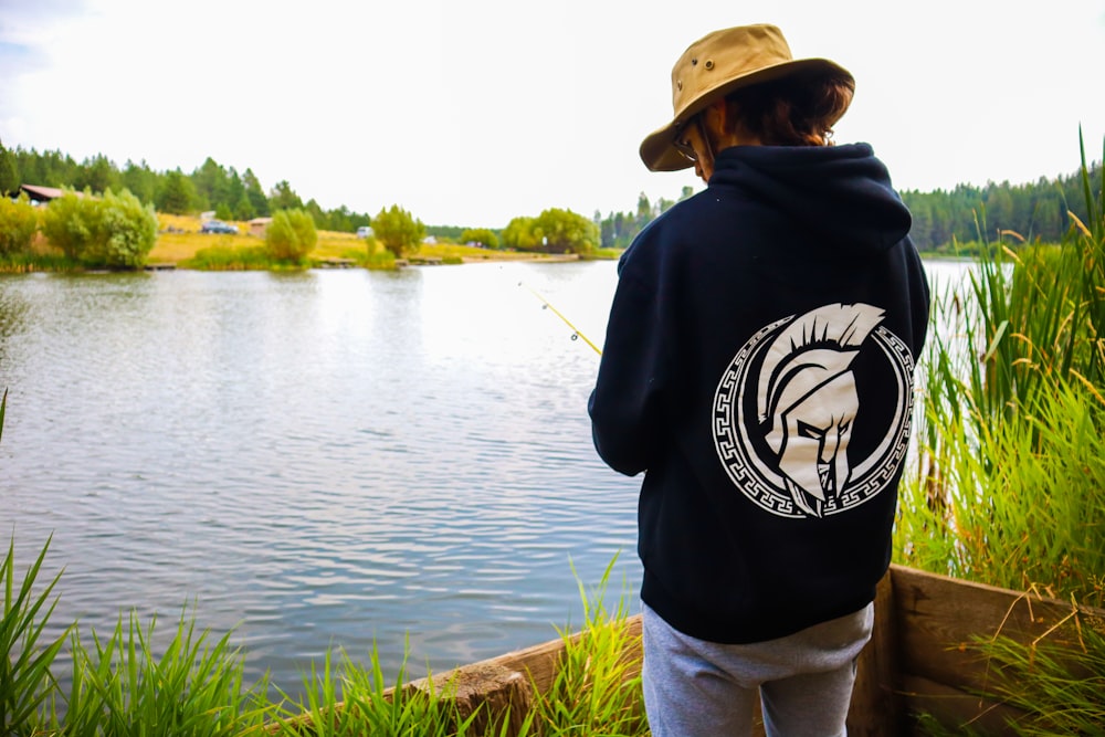 man in black hoodie standing near lake during daytime