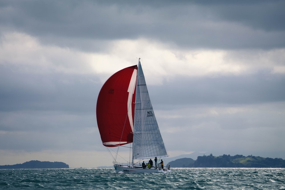 red and white sail boat on sea during daytime