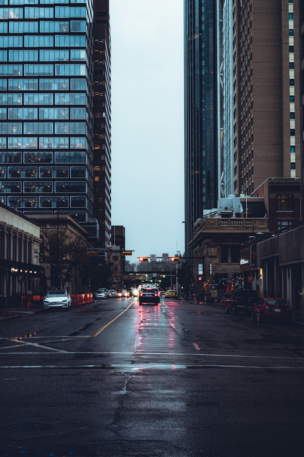 cars on road in between high rise buildings during daytime