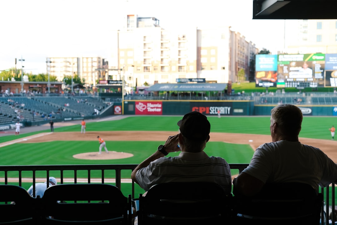 woman in white shirt sitting on chair watching baseball game during daytime