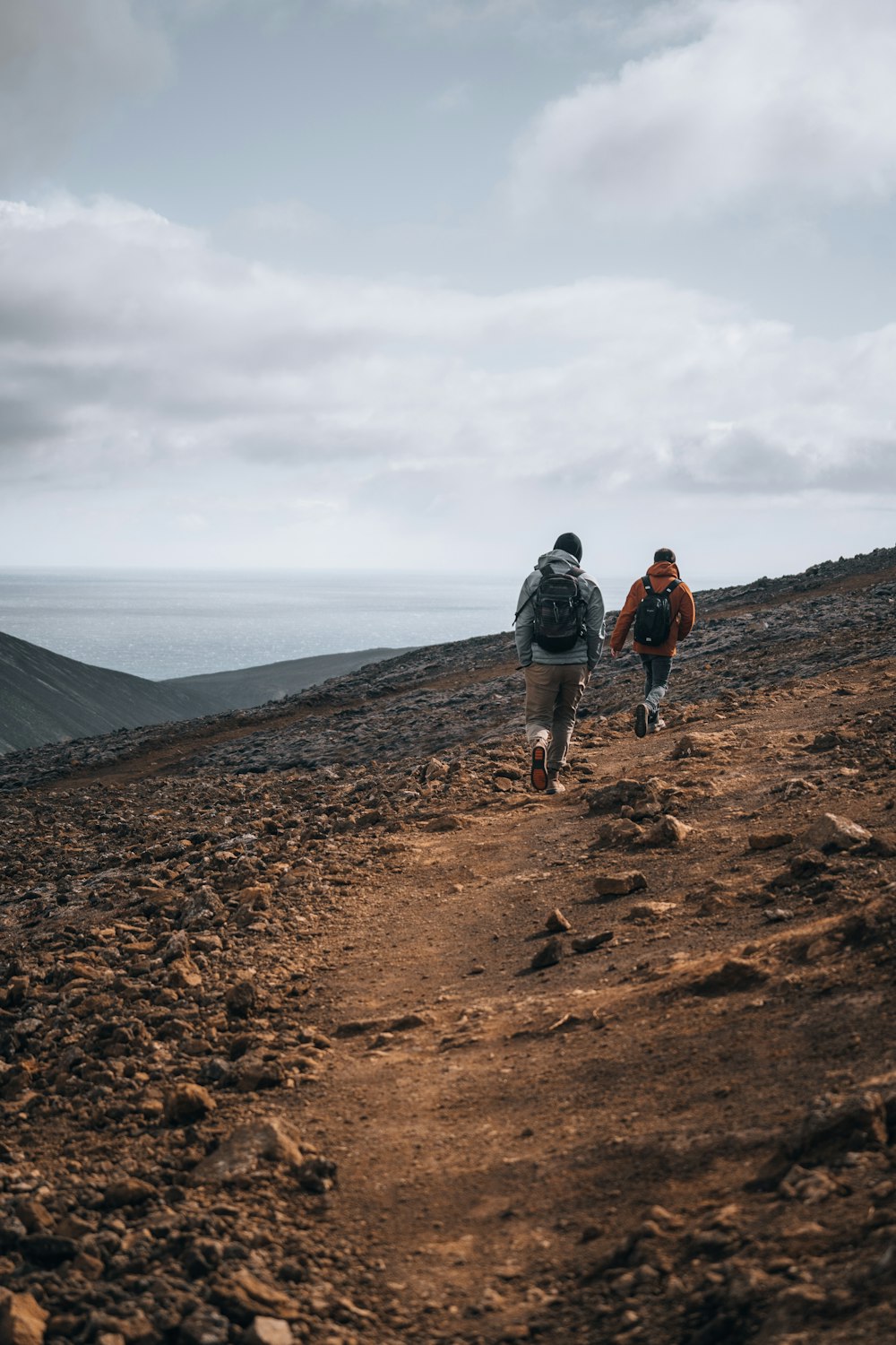 2 men walking on brown dirt road during daytime