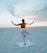 A serene setting with a person practicing yoga on a beach at sunrise.