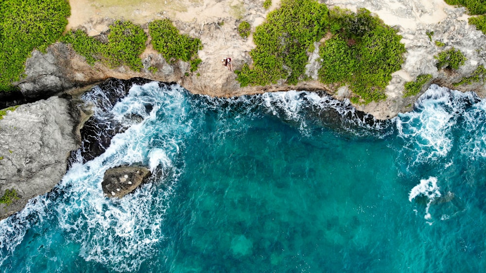 green and brown rock formation beside body of water during daytime