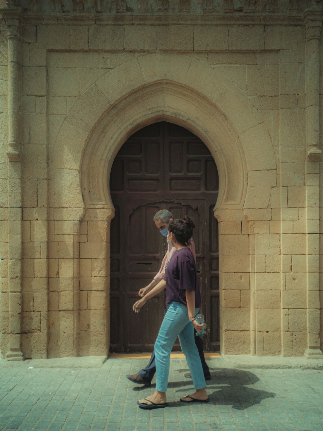 woman in blue denim jeans standing near brown concrete building during daytime
