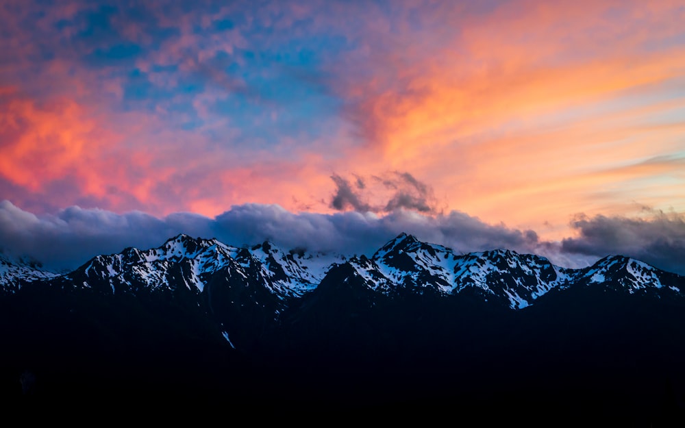 snow covered mountain under orange and blue sky