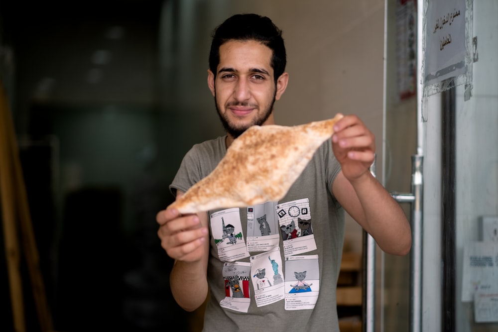 man in gray tank top holding pizza