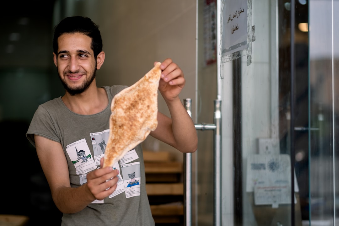 man in black tank top holding pizza