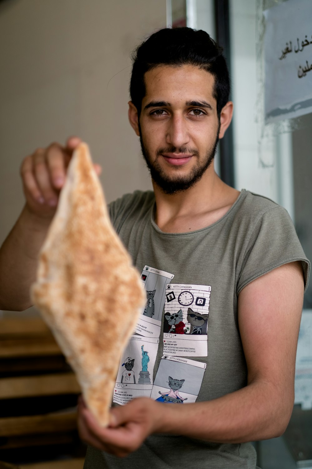 man in gray crew neck t-shirt holding sliced of pizza