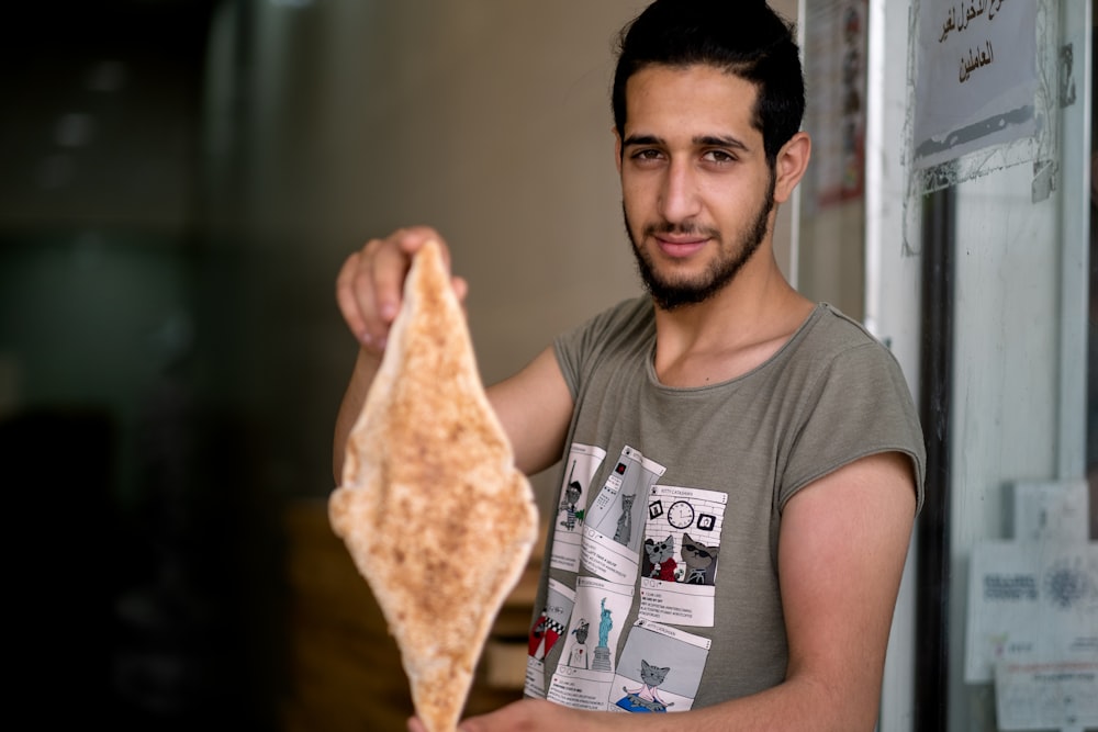 man in gray crew neck t-shirt holding pizza