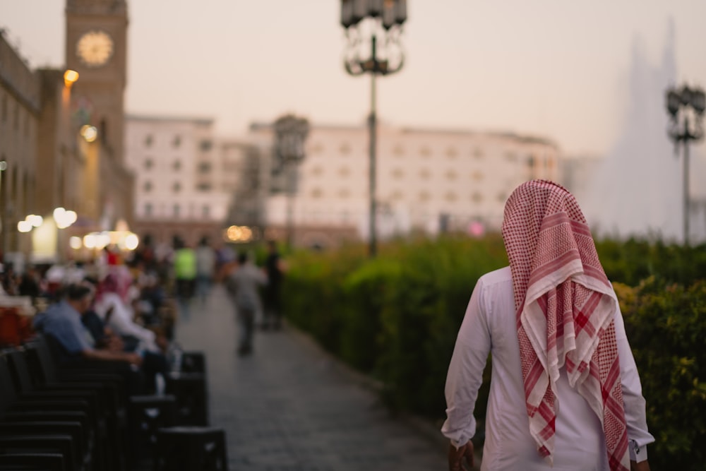 man in white long sleeve shirt standing on sidewalk during daytime