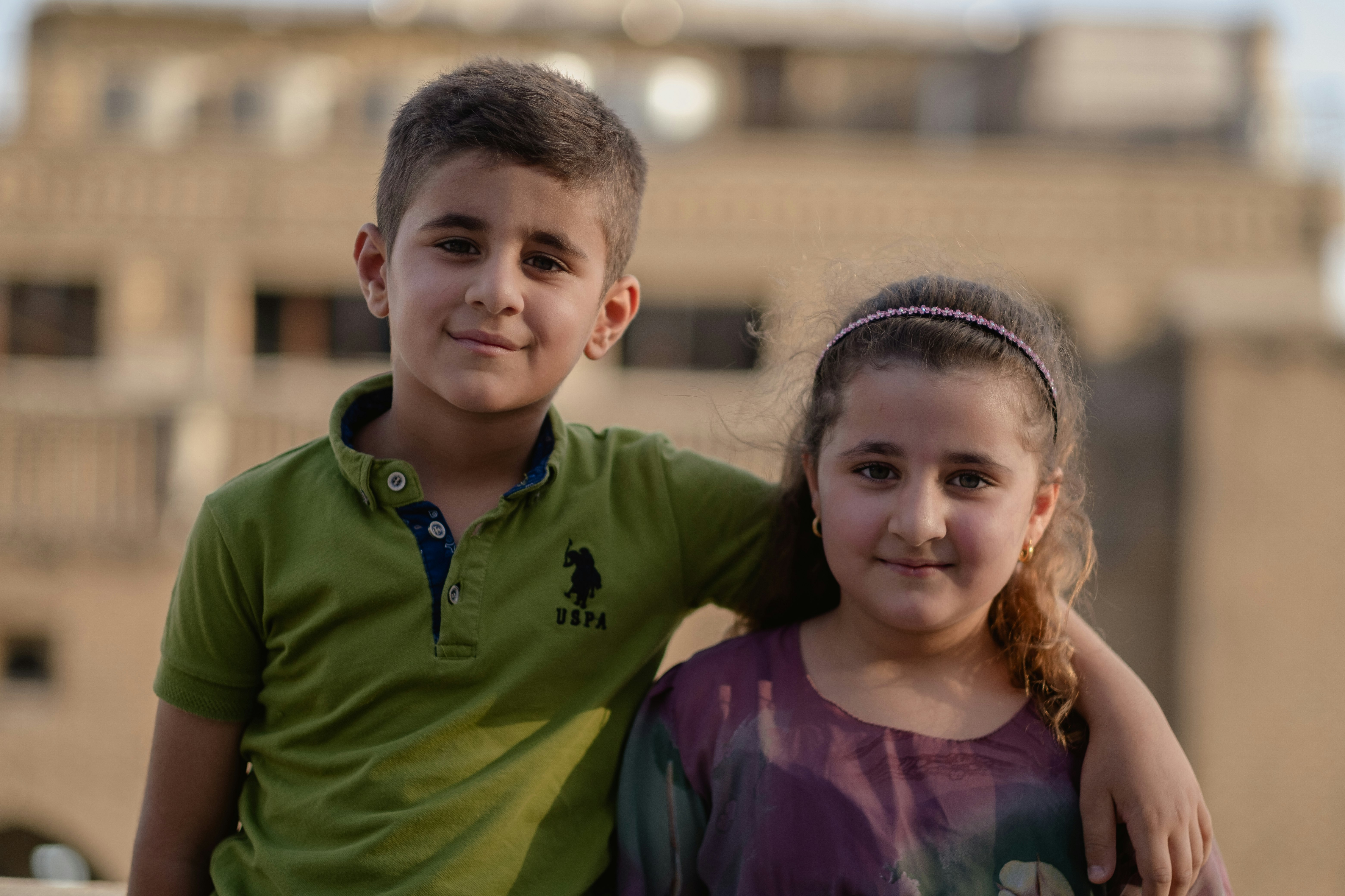 girl in purple crew neck shirt beside boy in green crew neck shirt