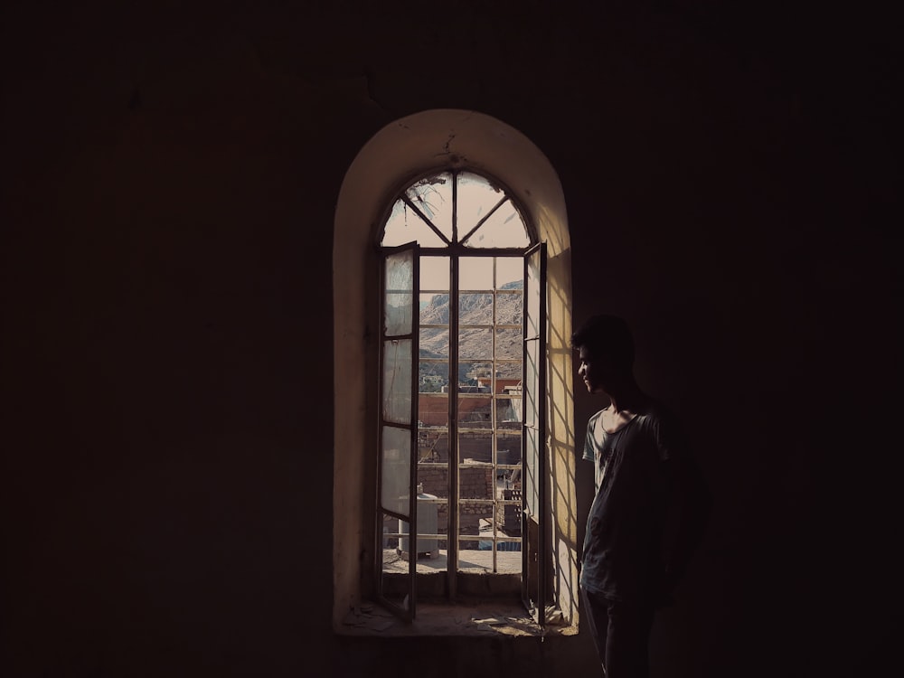 man in white dress shirt standing beside window