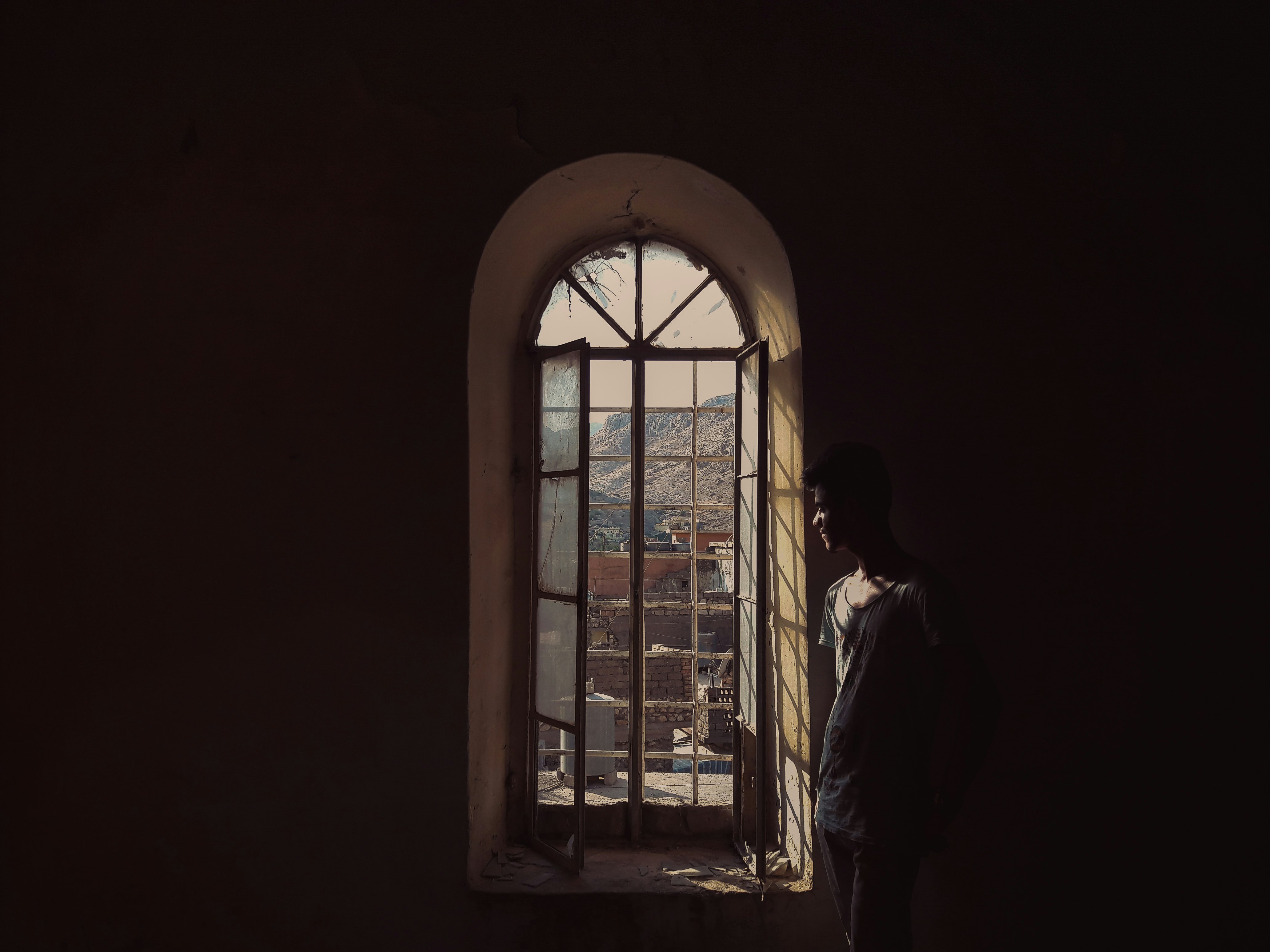 man in white dress shirt standing beside window