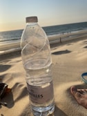 A group of 2L water bottles set against a sunny beach backdrop.