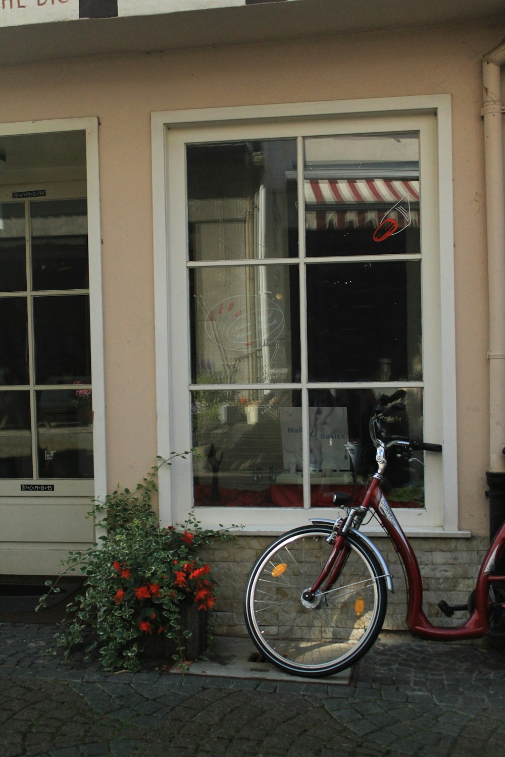 낮에는 흰색 콘크리트 건물 옆에 주차된 빨간색과 검은색 도시 자전거