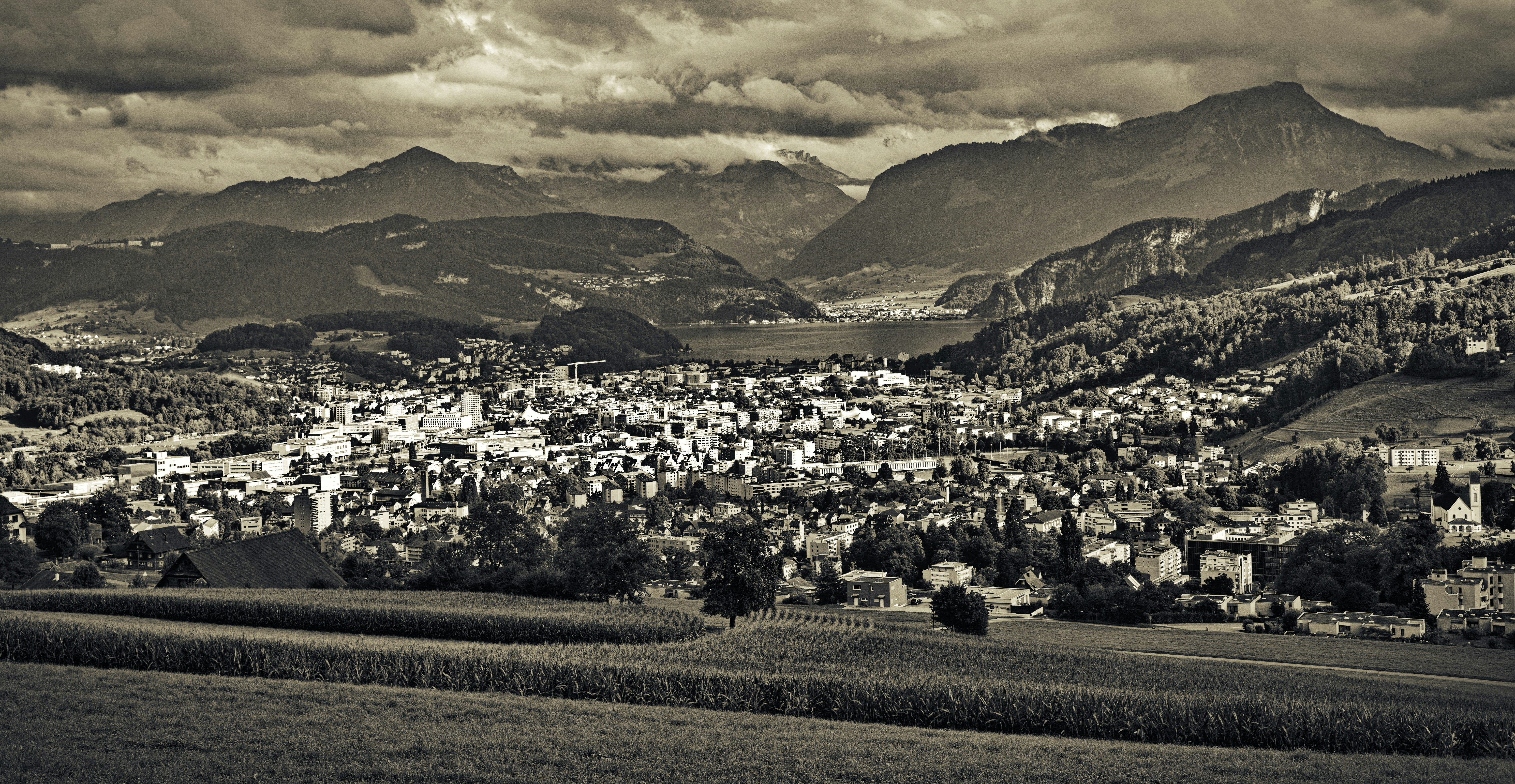 houses on green grass field near mountains under cloudy sky during daytime, 