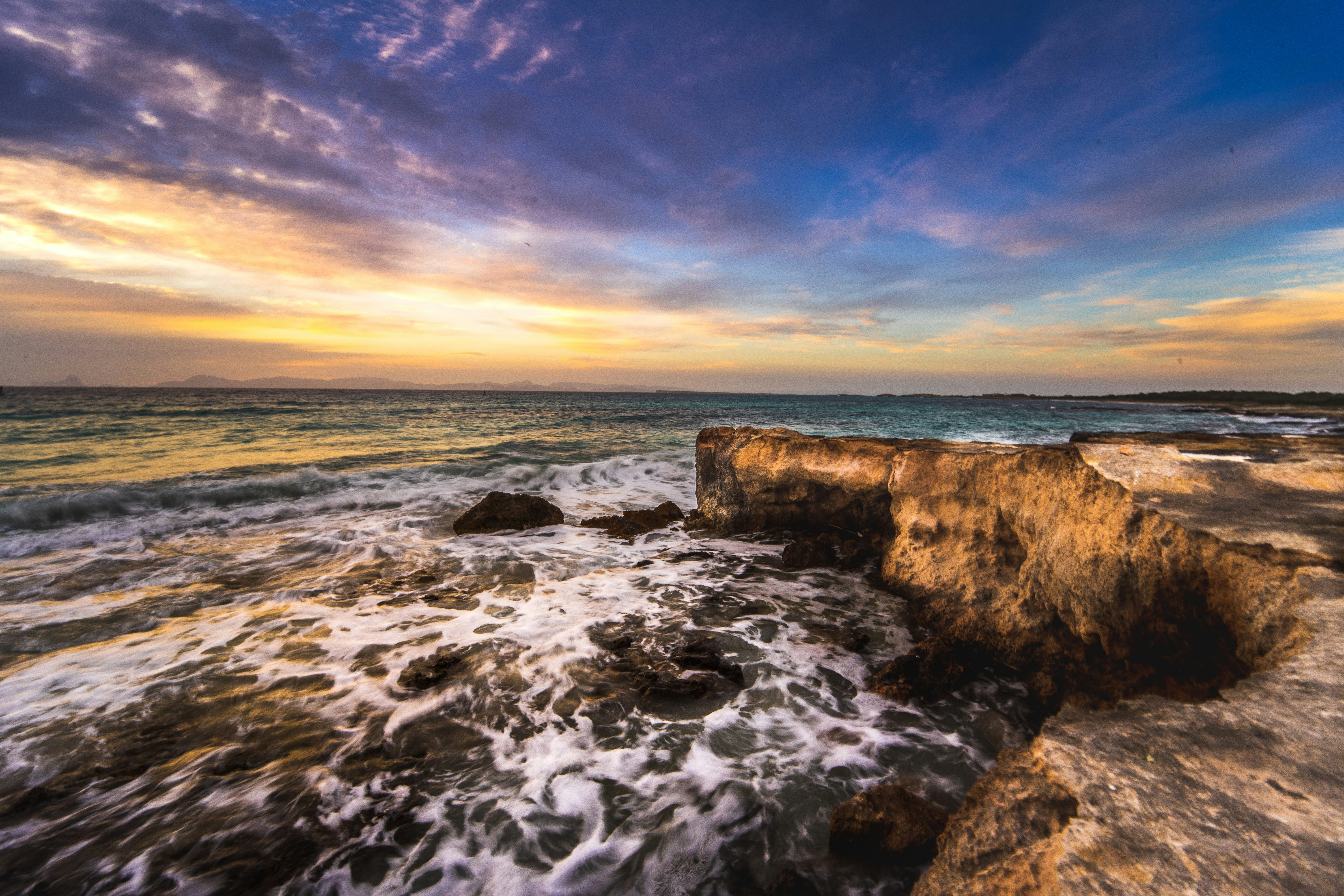 ocean waves crashing on rocks during sunset