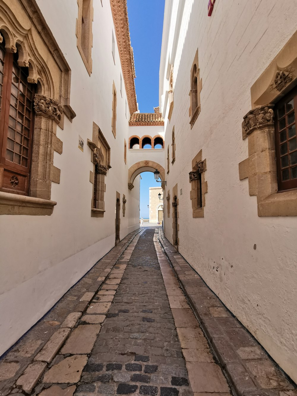 Camino de ladrillo marrón entre un edificio de hormigón blanco durante el día