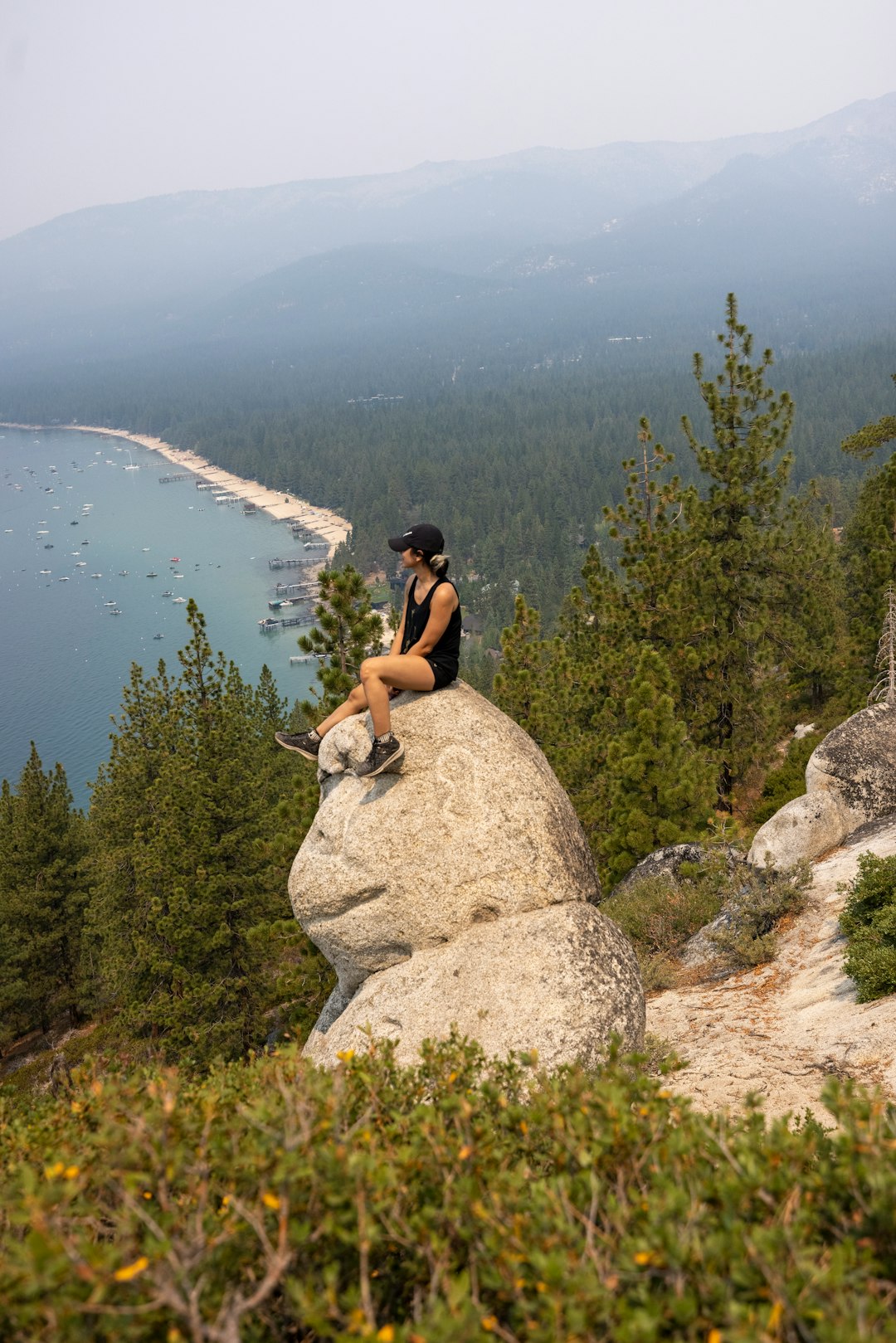 man in black t-shirt sitting on rock near lake during daytime