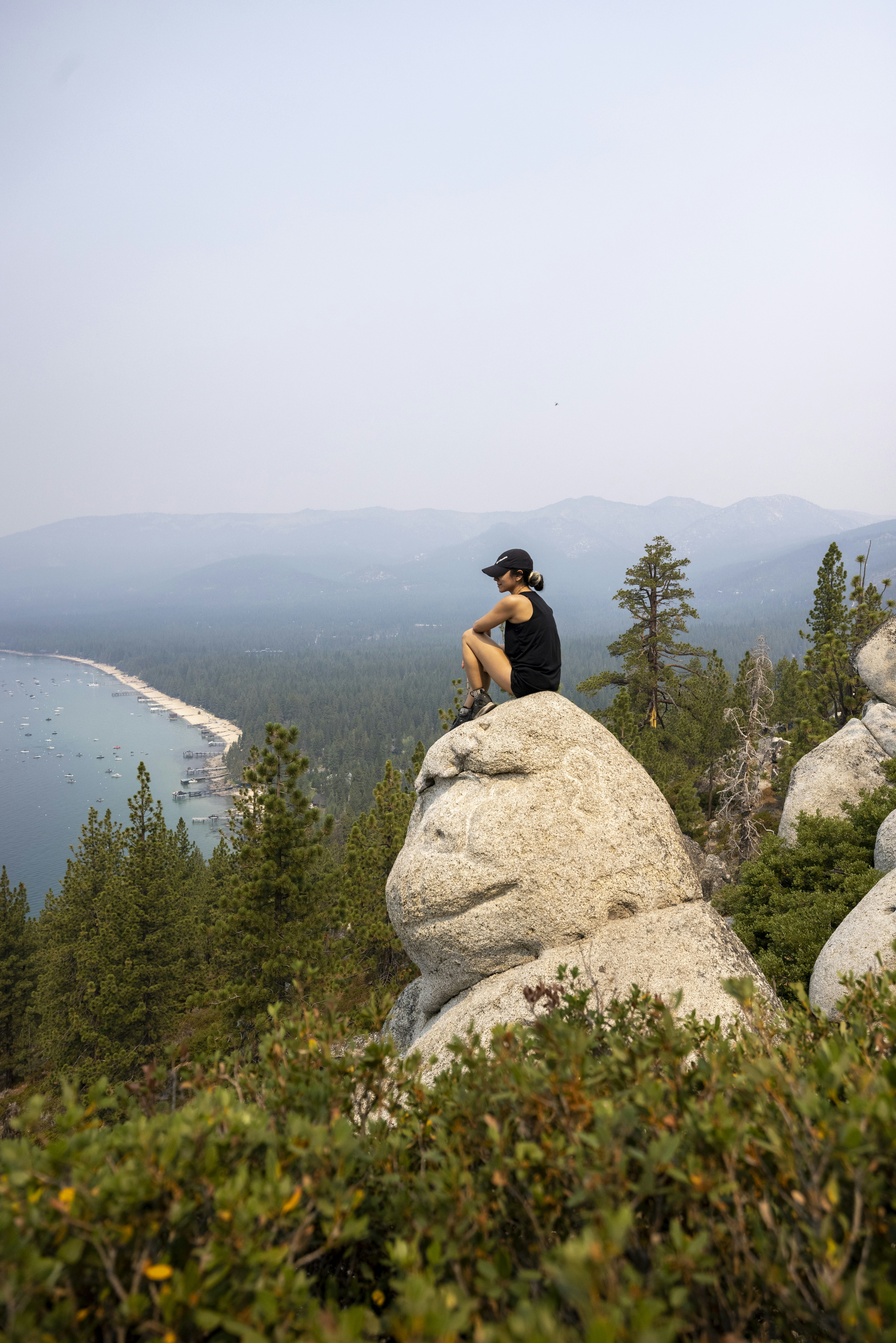 woman in black tank top sitting on rock formation during daytime