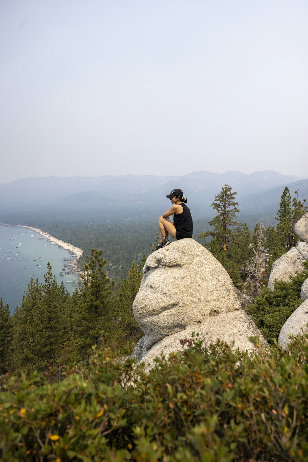 woman in black tank top sitting on rock formation during daytime