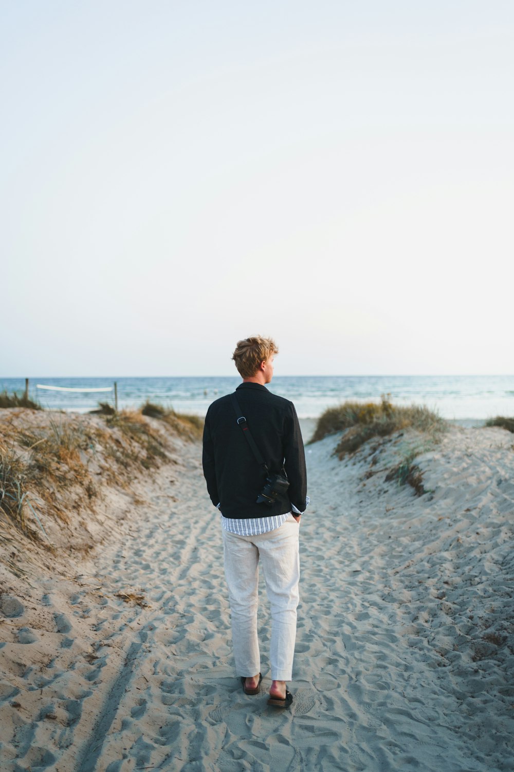 man in black jacket walking on gray sand during daytime