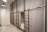 A room with multiple bunk beds, each enclosed with gray curtains for privacy. The beds are structured with black metal frames, and ladders are attached to access the upper bunks. The walls are white, and there's a full-length mirror on one wall. Ceiling lights with black shades provide illumination.