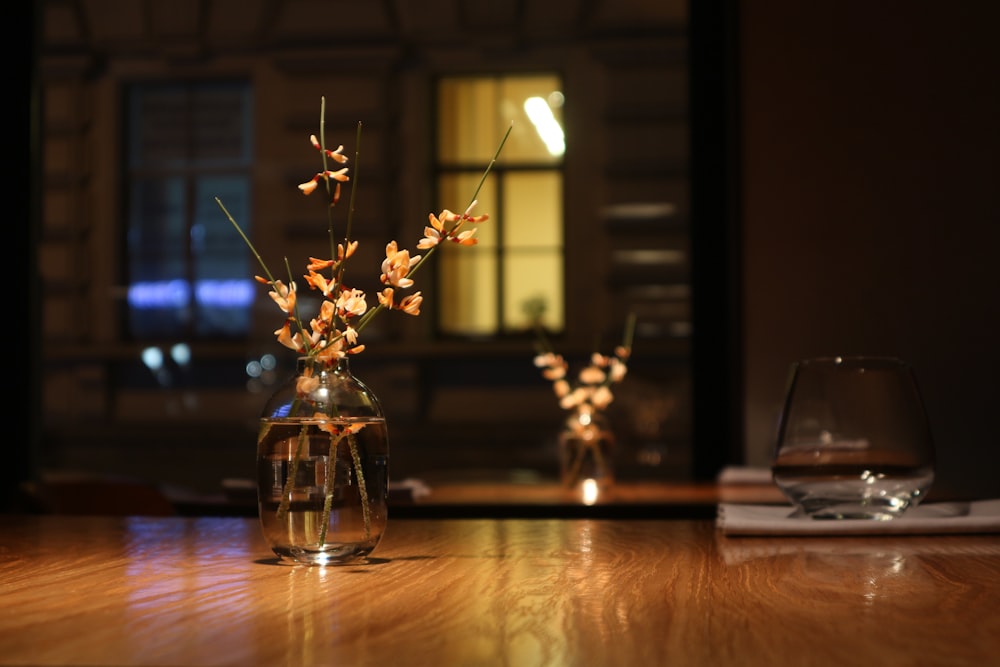 fiori bianchi in vaso di vetro trasparente su tavolo di legno marrone