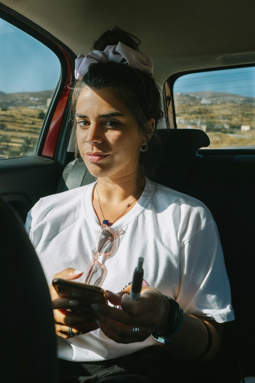 woman in white shirt holding smartphone