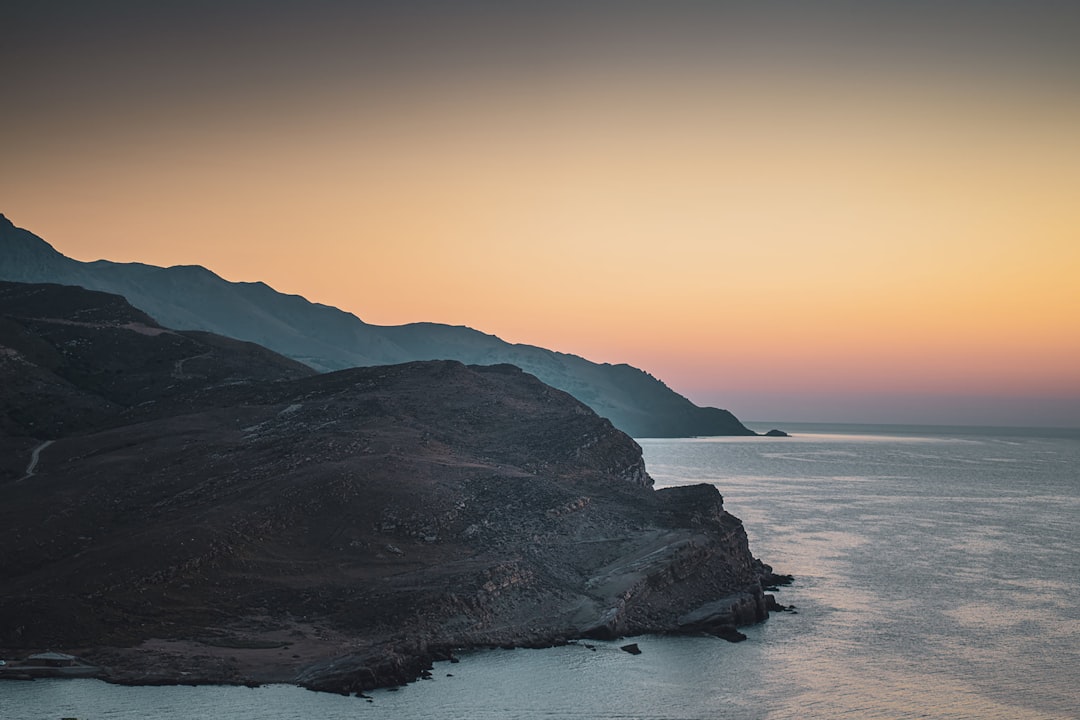 black mountain beside body of water during daytime