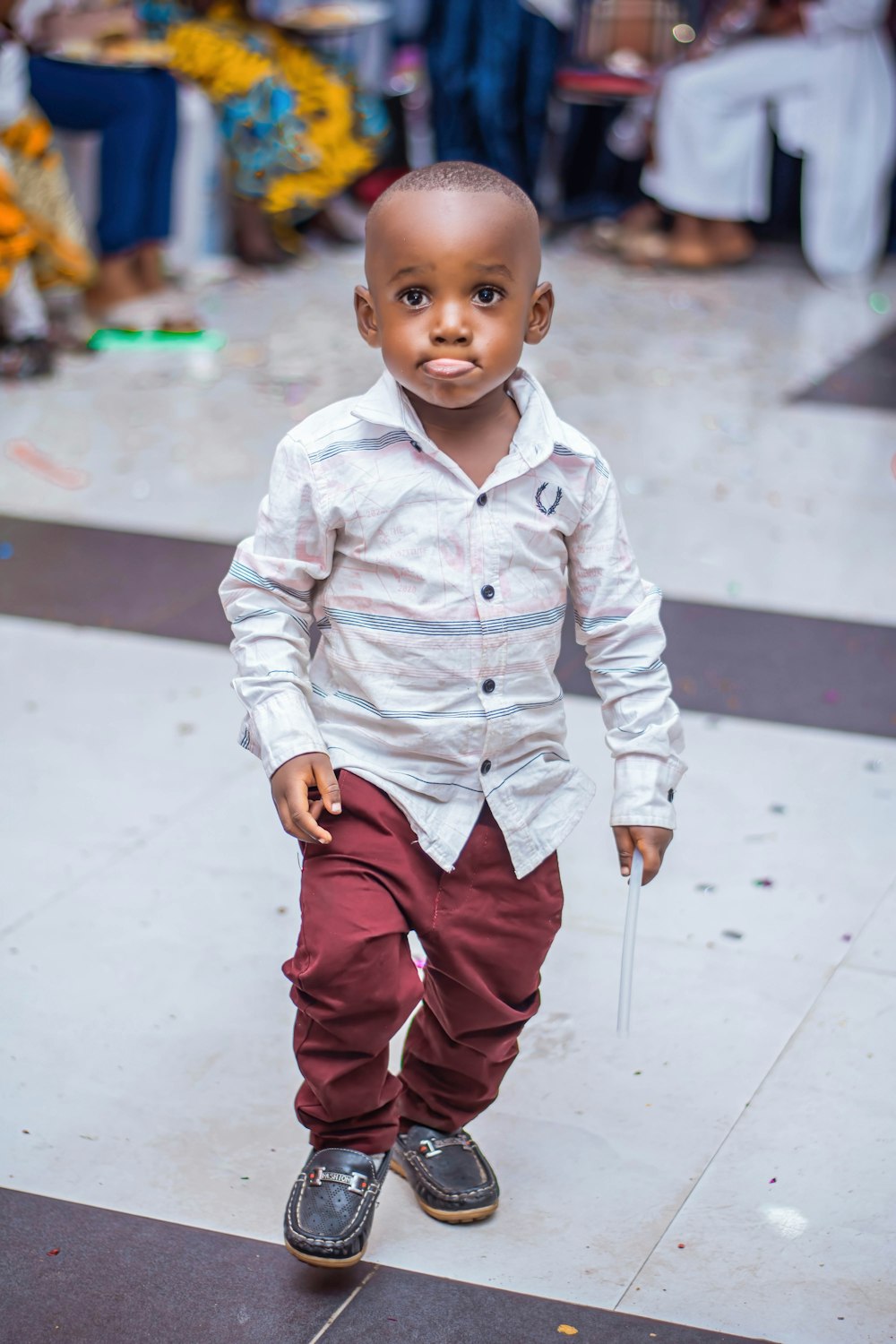 boy in white dress shirt and red pants standing on gray concrete floor during daytime