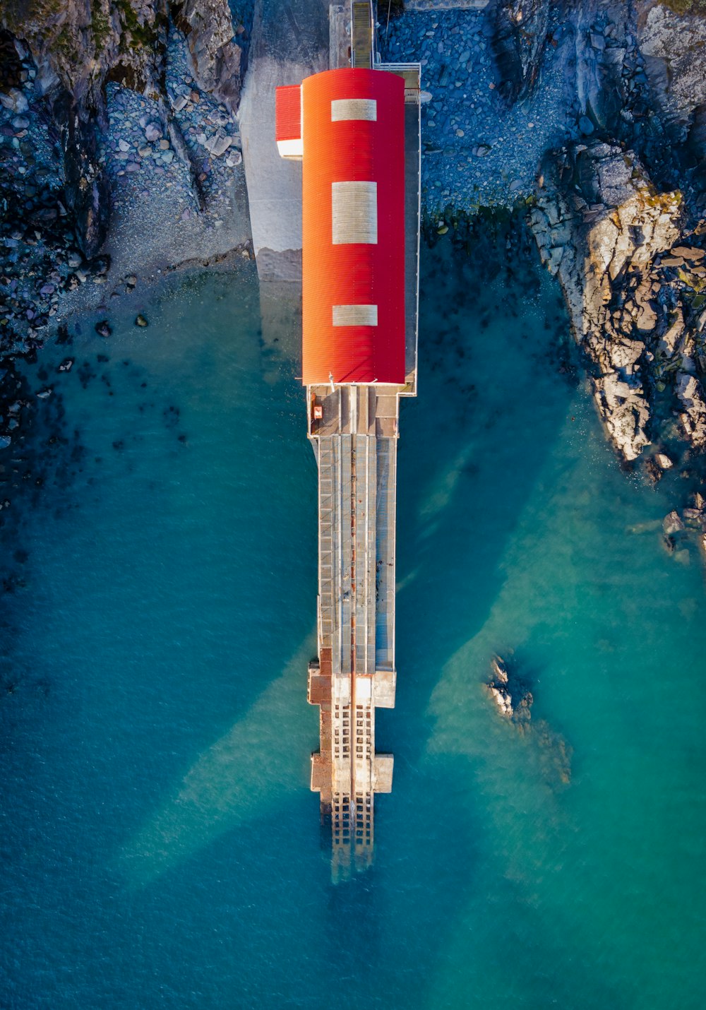 torre vermelha e branca perto do corpo de água durante o dia