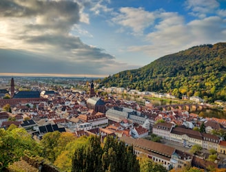 aerial view of city buildings near green mountain during daytime