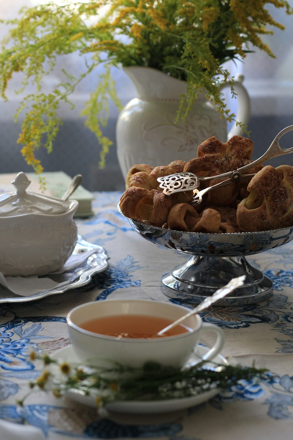 cookies on stainless steel bowl beside white ceramic teacup with saucer