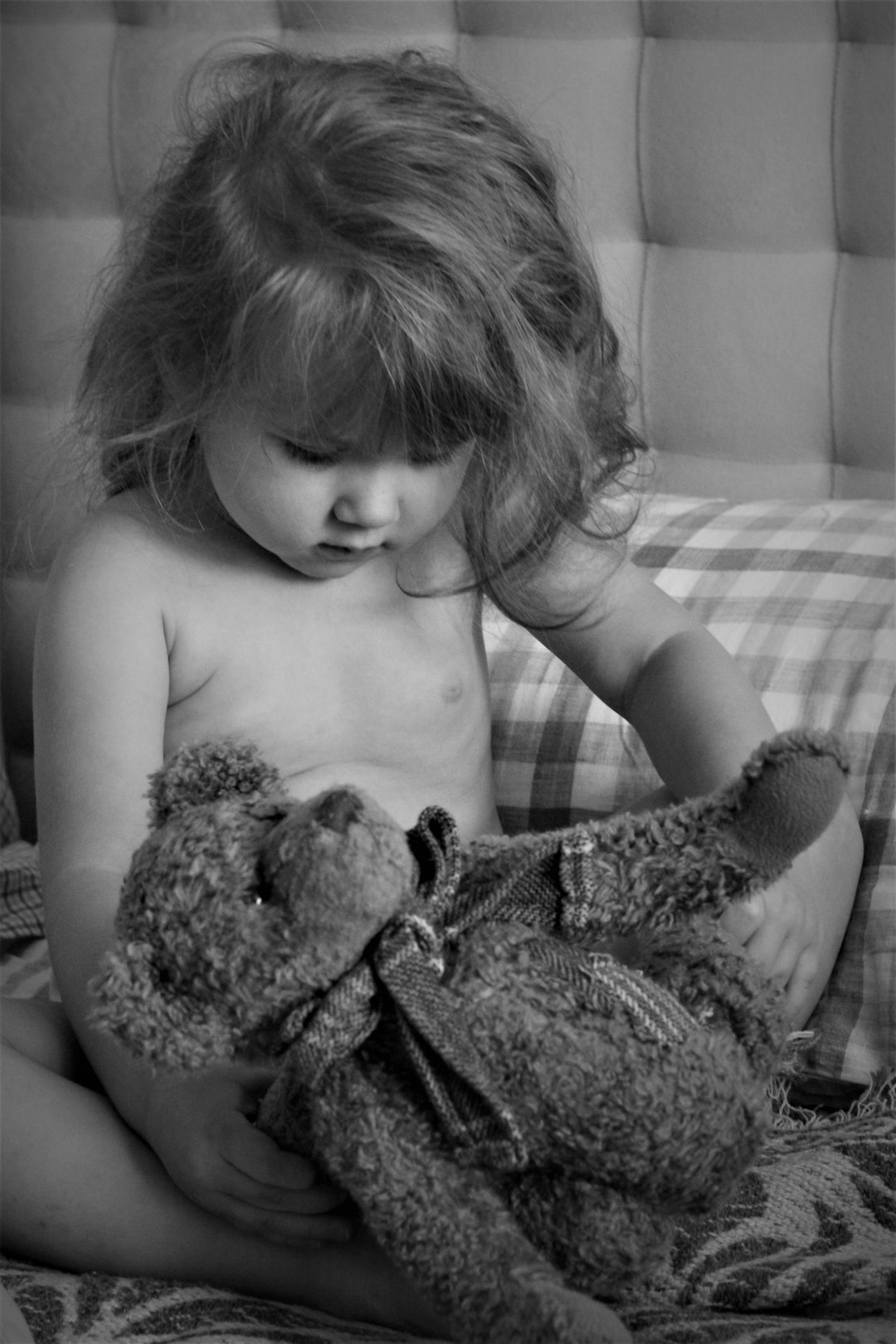 grayscale photo of child hugging bear plush toy