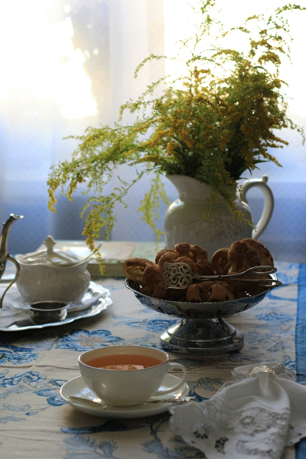 white ceramic teacup on saucer beside green plant
