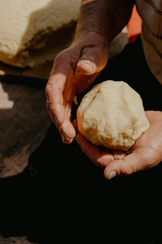 Close-up of hands gently shaping sourdough dough with natural light.