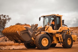 yellow and black heavy equipment on brown field during daytime