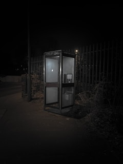 A mysterious old phone booth illuminated by a soft, eerie light at dusk.